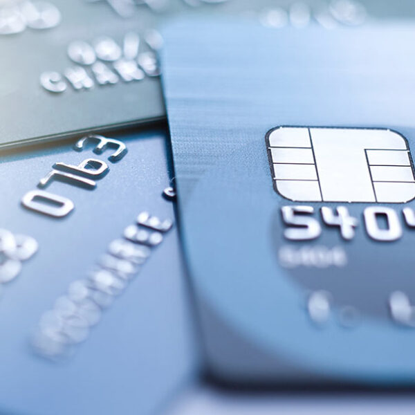 Close-up of multiple blue credit cards with EMV chips and embossed numbers visible.
