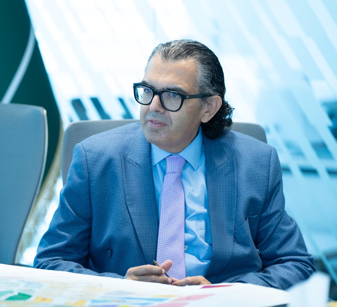 Real estate advisor in a suit with documents, seated at a modern office desk.
